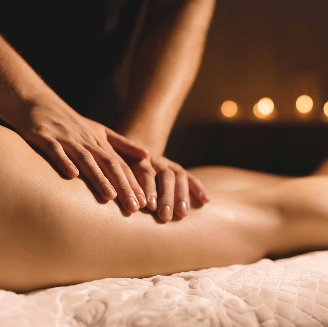 A masseur in a dark room does a hip massage with oil for a woman. Spa procedures massage women